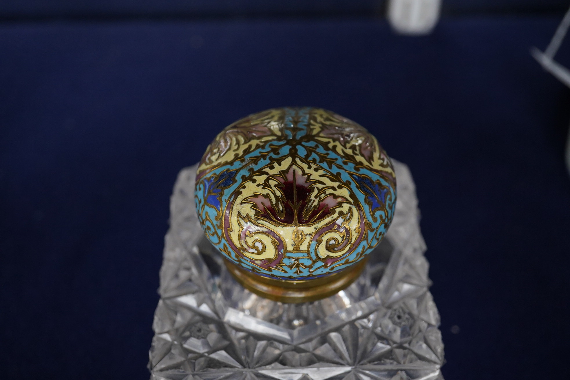 A large square glass inkwell, heavily cut with star cut base and octagonally cut top with enamelled brass hinged cover, 8cm wide. Condition - fair, some chipping